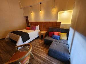 Habitación de hotel con cama y sofá en Hotel Consulado Petite Gallerie, en Guadalajara
