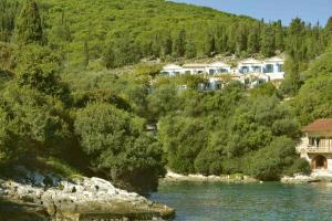 un groupe de maisons sur une colline à côté d'une rivière dans l'établissement KAMINAKIA Apartments - Adults only policy - Sun drenched - Heavenly peaceful - A soothing oasis with a large swimming pool exclusively for guests' use - Sheltered on both sides by an evergreen cypress forest - Stunning sea views from every veranda, à Fiskardho