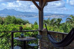a hammock on a balcony with a view of the ocean at Cocon de charme avec spa, proche de la plage in Les Trois-Îlets