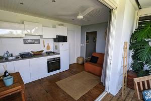 a kitchen with white cabinets and an orange chair in a room at Cocon de charme avec spa, proche de la plage in Les Trois-Îlets
