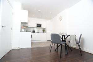 uma cozinha branca com mesa e cadeiras em Luxury Apartments in Central Watford em Watford