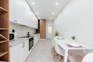 a kitchen with white cabinets and a table with chairs at Luxury Apartments “Dream City” in Uzhhorod