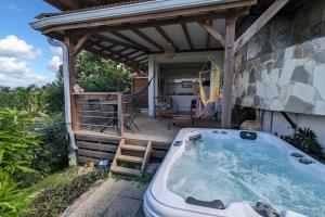 a hot tub on the patio of a house at Cocon de charme avec spa, proche de la plage in Les Trois-Îlets