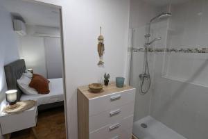 a white bathroom with a shower and a bed at Cocon de charme avec spa, proche de la plage in Les Trois-Îlets