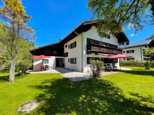 a large white building with red umbrellas in a yard at Forsthaus Reit im Winkl in Reit im Winkl