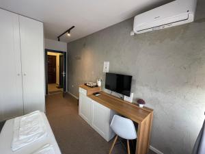 Habitación con escritorio y TV en la pared. en New Prishtina Luxury Rooms, en Pristina