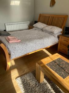 Schlafzimmer mit einem Bett mit einem Holzrahmen und einem Tisch in der Unterkunft Roblins Nest in Ammanford