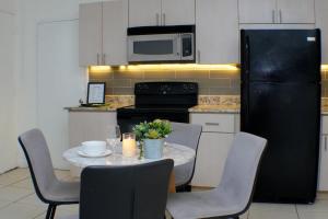 a kitchen with a table with chairs and a black refrigerator at Steps to the Beach Christmas Vacation Pool in Hallandale Beach