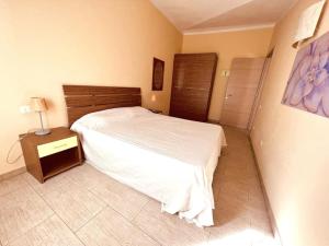 a bedroom with a white bed and a wooden headboard at Cozy Apartment with Pool, near Beach and Center in Santa Maria