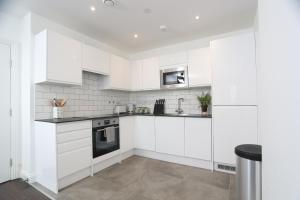 a white kitchen with white cabinets and appliances at Luxury Apartments in Central Watford in Watford