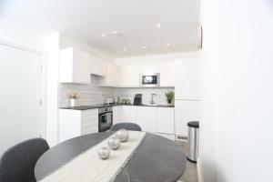 una cocina blanca con mesa y sillas. en Luxury Apartments in Central Watford, en Watford