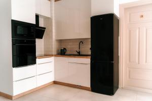 uma cozinha com um frigorífico preto e armários brancos em U Progu Lasu em Orzeszkowo