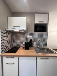una cocina con armarios blancos y fregadero en Le 28 Bis - Moderne & Confort, en La Roche-sur-Yon