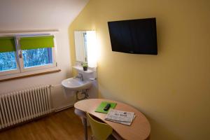 a room with a table and a sink and a television on the wall at Hotel Marthahaus in Bern