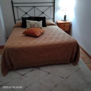 a bedroom with a bed with an orange pillow on it at Apartamento vacacional en la Alpujarra in Laroles