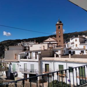 a group of white buildings with a clock tower at Apartamento vacacional en la Alpujarra in Laroles