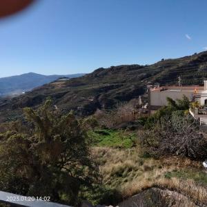 a view of a hill with a house and trees at Apartamento vacacional en la Alpujarra in Laroles