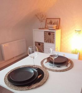 a table with two wine glasses and plates on it at Le p’tit Kerf proche Centre Ville in Quimper