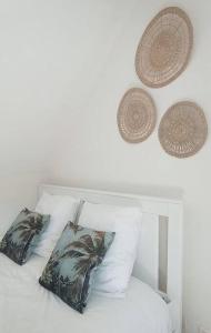 a white bed with two pillows and two baskets on it at Le p’tit Kerf proche Centre Ville in Quimper