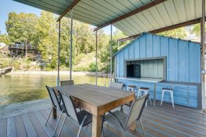 a wooden table and chairs on a deck next to the water at Spacious Lake of the Ozarks Escape with Deck and Views in Linn Creek