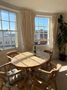 a dining room with a table and chairs and windows at Stunning town centre apartment with sea views in Worthing