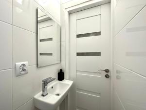 a white bathroom with a sink and a mirror at MMRent Desert Room in Gdańsk