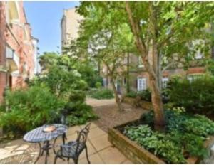 een patio met een tafel en stoelen en een boom bij Studio flat in the heart of St. Johns Wood in Londen