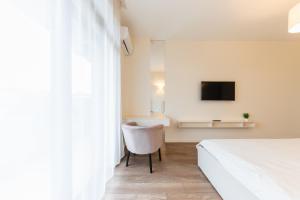 um quarto com uma cama, uma cadeira e uma televisão em Luxury Apartments “Dream City” em Uzhhorod