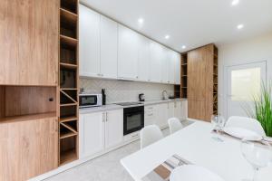 una cocina con armarios blancos y una mesa y sillas blancas. en Luxury Apartments “Dream City” en Úzhgorod