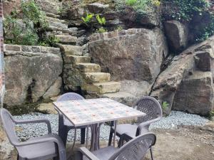 una mesa y sillas con una mesa y algunas rocas en Logement 2 à 4 pers - moulin en Saint-Carreuc