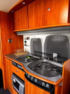 a stove top in a kitchen with wooden cabinets at Campervan romantic getaway in Old Town Brasov in Braşov
