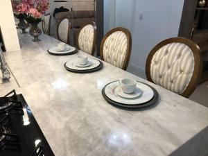 una mesa con dos tazas, platos y sillas en Beverly Hills House, en Curitiba