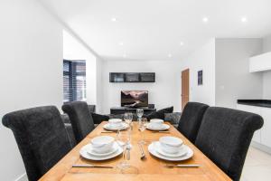 a dining room with a wooden table and black chairs at Luxury Apartment in Town Centre with Free Gated Parking in Potters Bar
