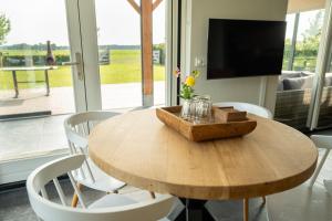 a wooden table with white chairs and a television at Vakantieverblijf Weidezicht in Dorst
