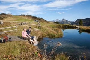 a man and woman sitting on a rock next to a river at Boutique Hotel Hohes Licht in Damuls