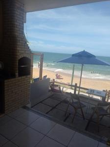 une terrasse avec un parasol, des chaises et une plage dans l'établissement Casa de Praia PÉ NA AREIA em Rio das Ostras RJ, à Rio das Ostras