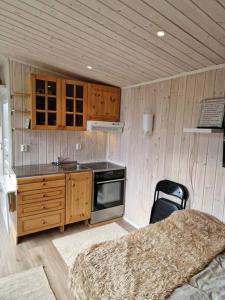 uma cozinha com armários de madeira e uma cama num quarto em Sjarmerende anneks i Sigerfjord, Vesterålen em Sortland