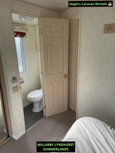 a bathroom with a toilet and a window and a door at WILLERBY LYNDHURST in Lincolnshire