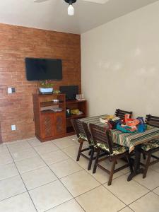 uma sala de estar com uma mesa e cadeiras e uma televisão em Casa de Praia PÉ NA AREIA em Rio das Ostras RJ em Rio das Ostras