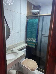 La salle de bains est pourvue d'un lavabo et d'une douche avec un miroir. dans l'établissement Casa de Praia PÉ NA AREIA em Rio das Ostras RJ, à Rio das Ostras