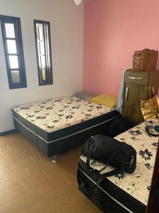 a bedroom with two beds and a bag on the floor at Casa de Praia PÉ NA AREIA em Rio das Ostras RJ in Rio das Ostras