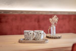zwei Kaffeetassen auf einem Holztisch mit einer Vase in der Unterkunft Plattner-Hof in Petersberg