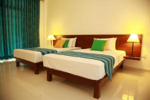 two beds in a hotel room with green and white at Samwill Holiday Resort in Kataragama