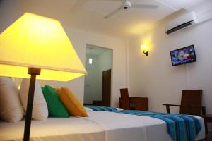 um quarto com uma cama com um candeeiro amarelo em Samwill Holiday Resort em Kataragama