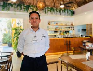 Ein Mann steht in einem Restaurant mit gekreuzten Armen in der Unterkunft Hotel Chablis Palenque in Palenque