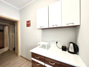 a kitchen with white cabinets and a coffee pot on a counter at MMRent Spring Room in Gdańsk