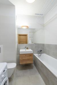 a bathroom with a sink and a tub and a toilet at Przytulny apartament z parkingiem in Łódź