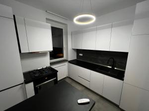 a kitchen with white cabinets and a sink and a stove at Neversea Suite in Constanţa