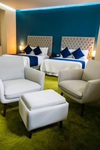 una camera d'albergo con due letti e due sedie di HOTEL MARGARITA a Puebla