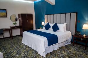 Habitación de hotel con cama grande y paredes azules en HOTEL MARGARITA en Puebla
